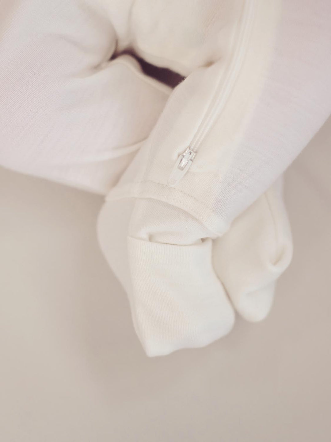 merino baby sleepsuit white detail #colour_pure-ivory